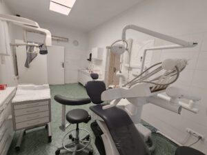 Wnętrze gabinetu stomatologicznego z fotelem dentystycznym i sprzętem medycznym.