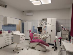 Wnętrze gabinetu stomatologicznego z fotelem dentystycznym i sprzętem medycznym.